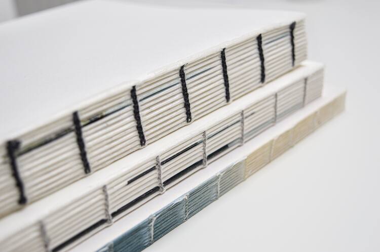 Drie hand gebonden boeken boeken liggen op een stapeltje.