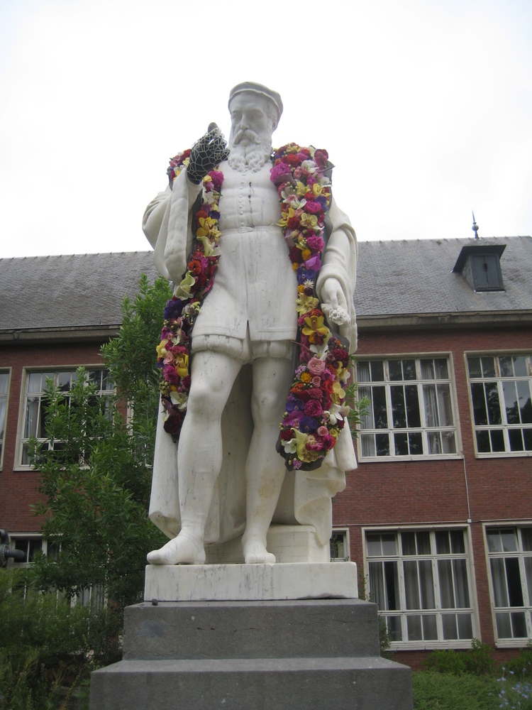 Wit marmeren standbeeld van Dodoens, versierd met een sjaal gemaakt uit bloemen.