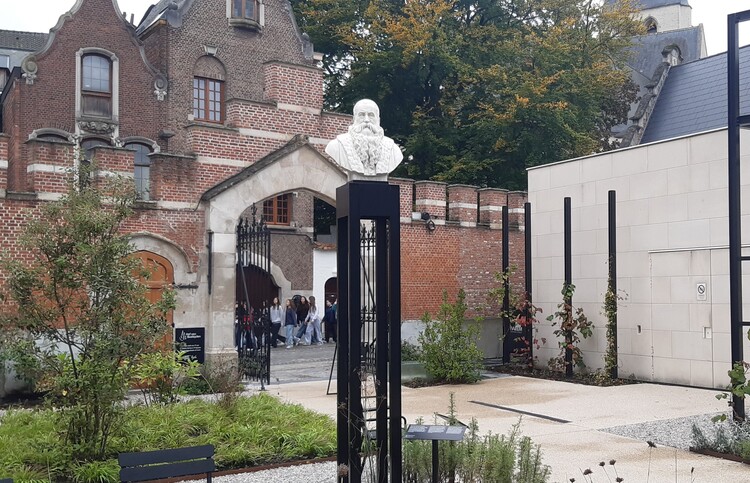 Museumtuin waar centraal, op een hoge zwart metalen pilaar, een borstbeeld van Dodoens staat.
